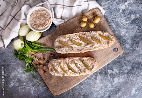 Sandwiches with meat pate and pickled cucumber on a wooden cutting board, top view. Rustic composition with pate. 
