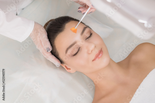 Cosmetic procedure. Chemical peeling. Doctor's hand with a brush touching the face of a young beautiful woman. Facial skin care. Place for text.