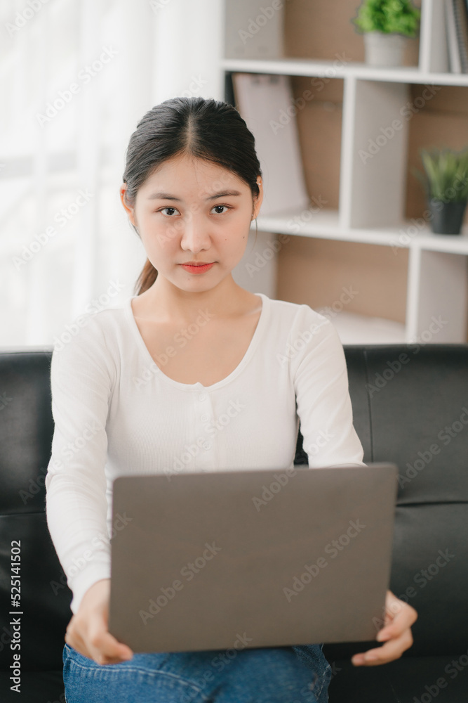 Asian woman happy holding laptop phone sitting sofa smiling good mood indoors indoors