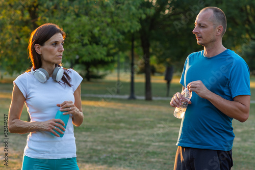 Modern couple making pause in an urban park during jogging, exercise.