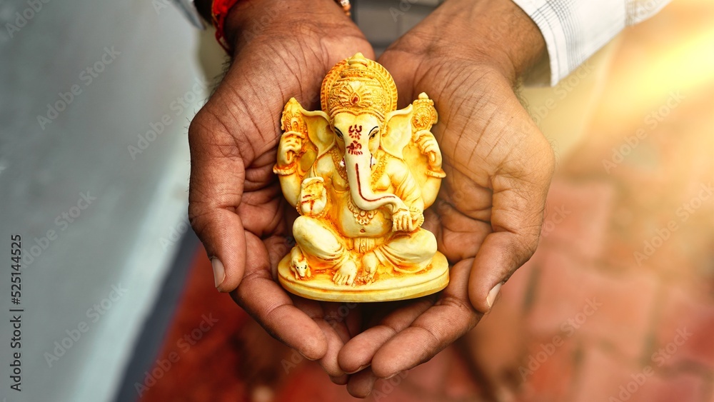 Hands holding Lord Ganesha idol in palm background for Visarjan or