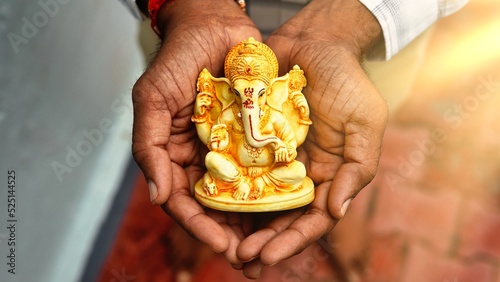 Hands holding Lord Ganesha idol in palm background for Visarjan or Immersion. Lord Ganapati idol Annual ritual during Ganesh Chaturthi Hindu festival with sun rays. Ganesh utsav in Rajasthan India photo