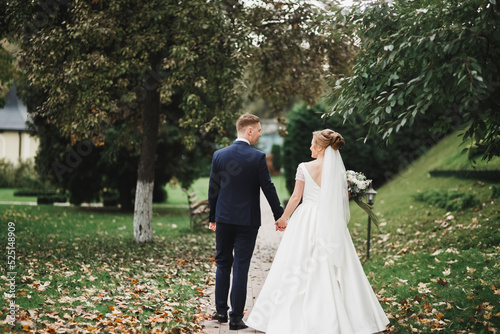 Romantic, fairytale, happy newlywed couple hugging and kissing in a park, trees in background