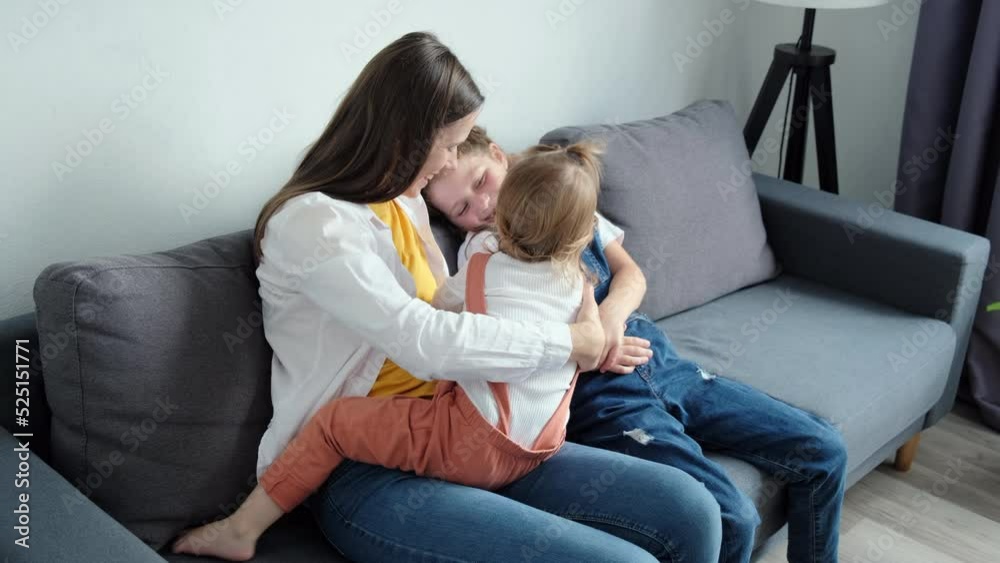 Playful happy young mom playing with two pretty little daughters, mother enjoy time on weekend with kids girls tickles laughing together seated on comfy sofa at home. Activities with child concept Playful happy young mom playing with two pretty little daughters, mother enjoy time on weekend with kids girls tickles laughing together seated on comfy sofa at home. Activities with child concept