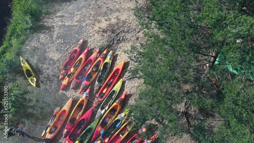 Aerial view of camping with kayaks on the beach of river on a sunny day. Nature background. Active rest concepts. Modern kayaks with paddles on beach near river. Summer camp activity.