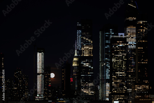 Panoramic view New York City Manhattan Hudson Yard skyscrapers and bright full moon behind buildings . High quality photo