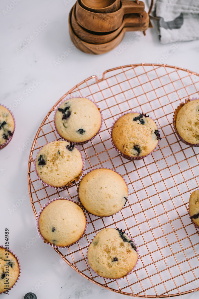 Homemade blueberry muffins baked to perfection on cooling rack in modern white marble kitchen. Homemade blueberry muffins baked to perfection on cooling rack in modern white marble kitchen.