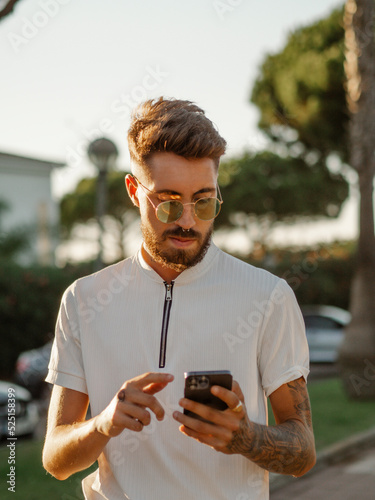 Hombre joven con tatuajes usando su teléfono móvil