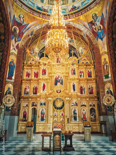 The altar and beautiful painted interior of the Curchi Monastery. Suspending golden chandelier with glowing lights. Different icons of saints as traditional for Christian Orthodox churches in Moldova photo