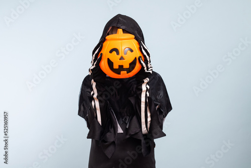 Happy Halloween! Cute little boy in a costume with a pumpkin basket jack-o-lantern