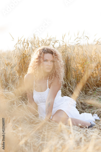 a beautiful girl in a white sundress is resting in a field of rye