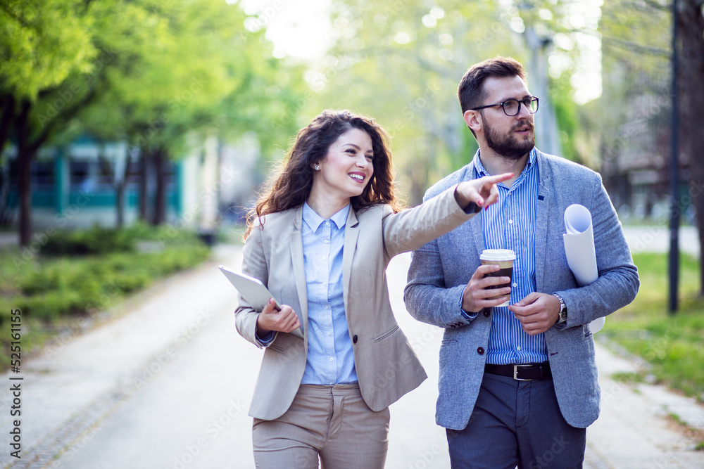 Business couple walking in a park and discussing Business couple walking in a park and discussing