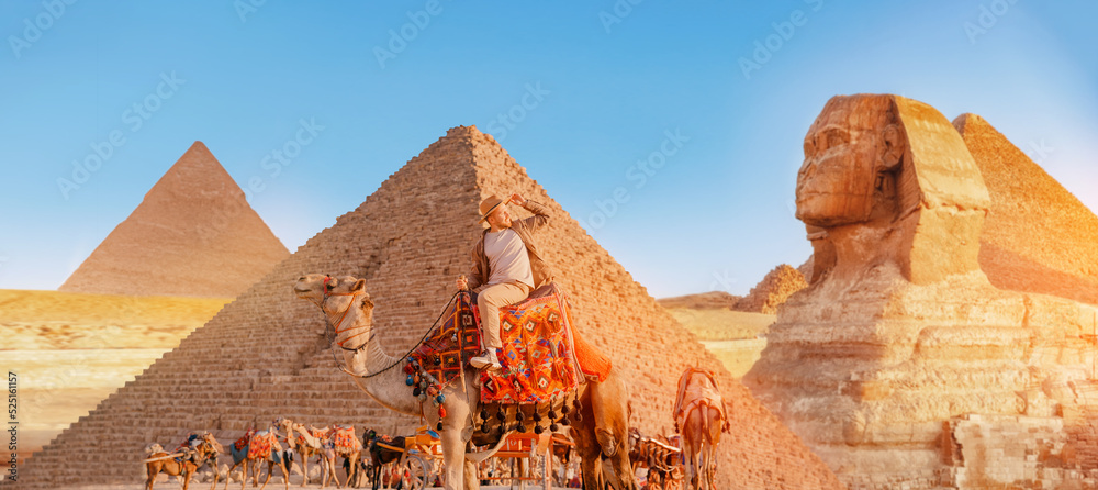 Happy Tourist man with hat riding on camel background pyramid of Egyptian Giza, sunset Cairo, Egypt - obrazy, fototapety, plakaty 
