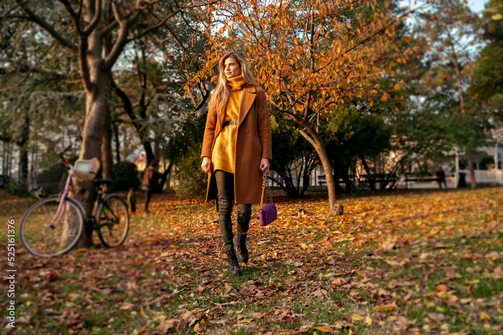Slim fashionable beautiful girl walking through the park in autumn 