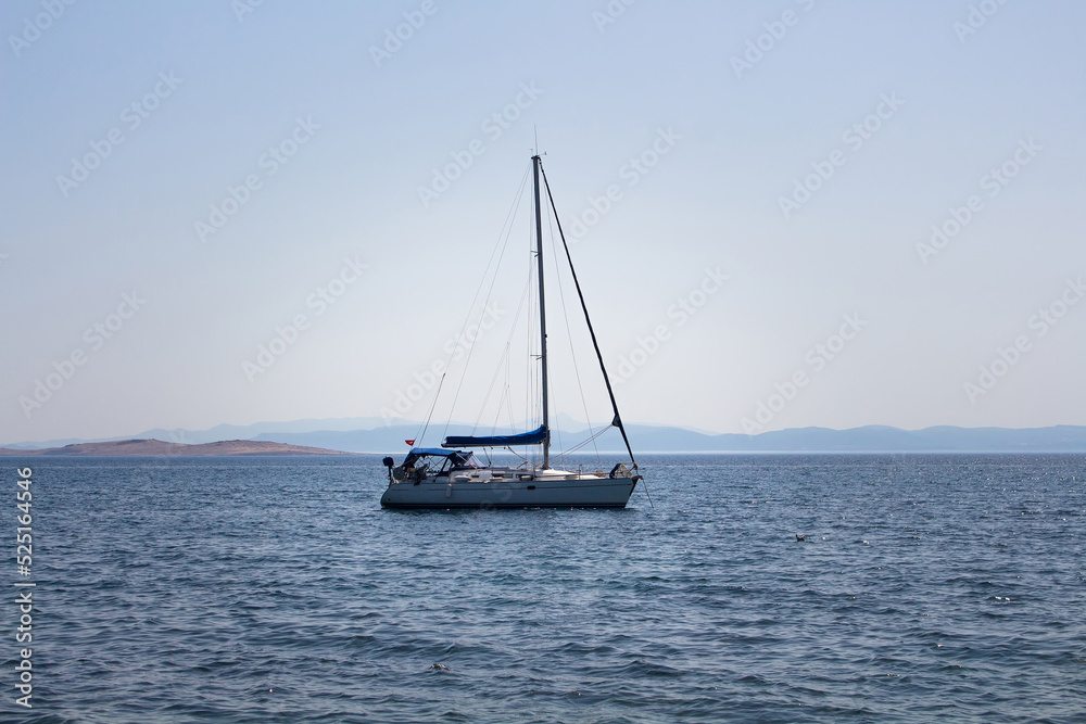 View of a sail boat, Aegean sea and landscape captured in Ayvalik area of Turkey. It is a sunny summer day.