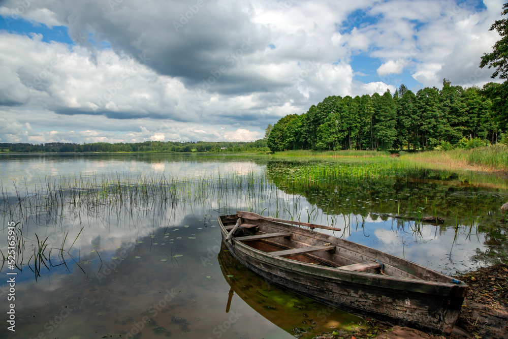 Old wooden boat on the forest lake in Aluksne. Aluksne Lake is a eleventh largest lake in Latvia and a place for rest and relaxation in Aluksne. Latvia Old wooden boat on the forest lake in Aluksne. Aluksne Lake is a eleventh largest lake in Latvia and a place for rest and relaxation in Aluksne. Latvia