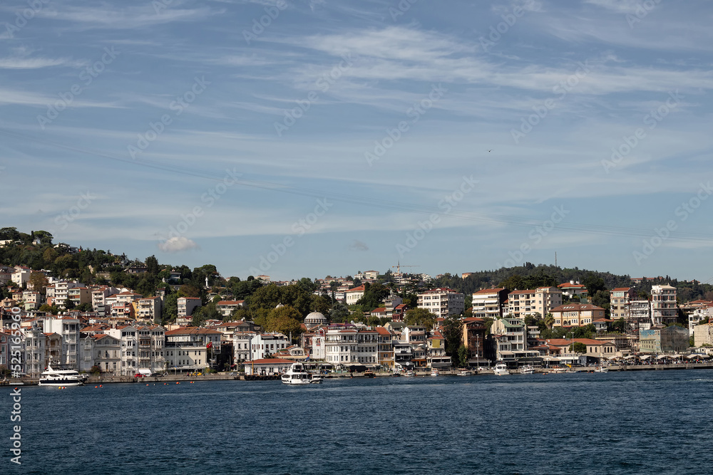 View of moored boats on Bosphorus and Arnavutkoy neighborhood on European side of Istanbul. It is a sunny summer day. Beautiful travel scene.