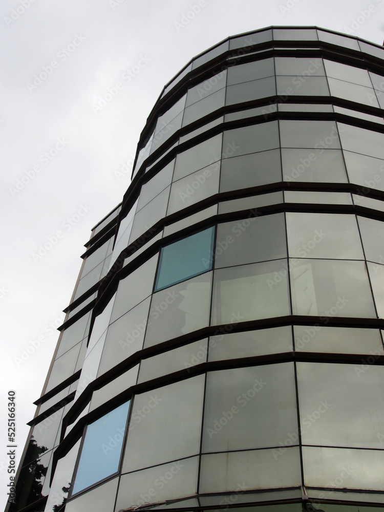 The glazed facade of a high-rise building against a gray, harsh winter sky. Styles of modern architecture, glass and metal.