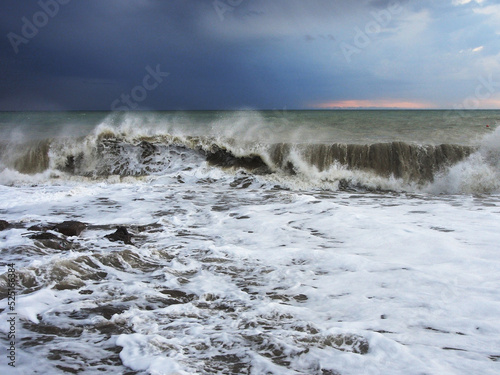 Cold stormy sea waves rush onto the shore covered with large pebbles. Landscape photography, a variety of landscapes, travel.