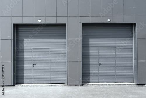 Two entrances with lifting gates in a modern building with a gray facade. There are doors. Background. Architecture.