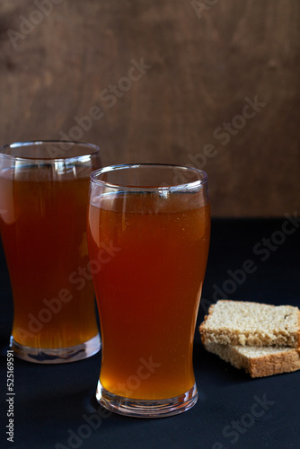 glass of beer and sandwich on the wooden table. two high Glasses of fresh kvass with bread on black background with copy space. vertical