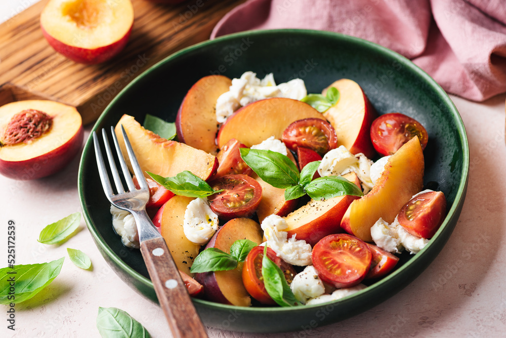 Healthy summer fruit and cheese salad with peach, mozzarella, cherry tomatoes and basil