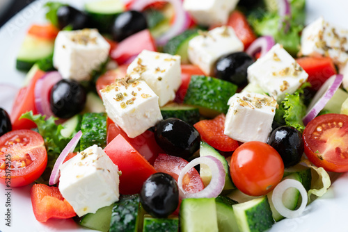 Greek salad with feta and black olives as background, closeup view