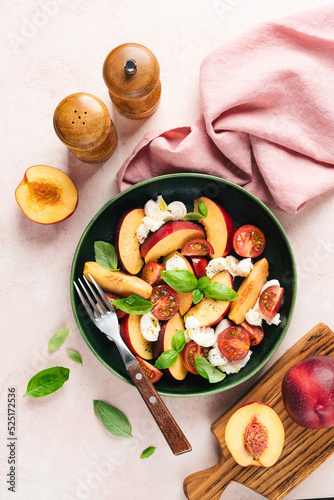 Healthy summer fruit and cheese salad with peach, mozzarella, cherry tomatoes and basil. Top view