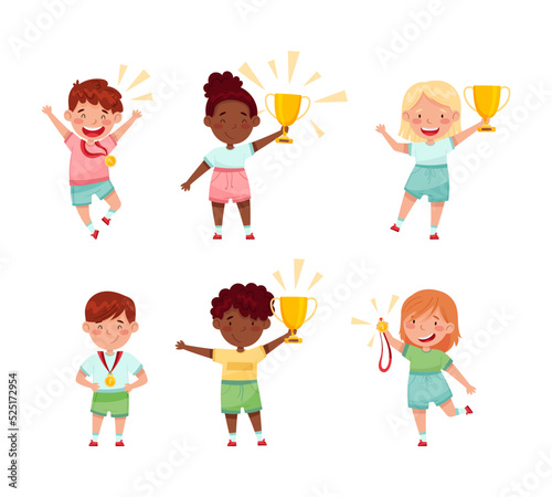 Cute little kids athletes holding trophy cups and medals set. Happy boys and girls celebrating win cartoon vector illustration