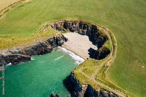 Aerial view of a tiny sandy beach surrounded by cliffs on the coast of Wales (Gwbert, Pembrokeshire) photo