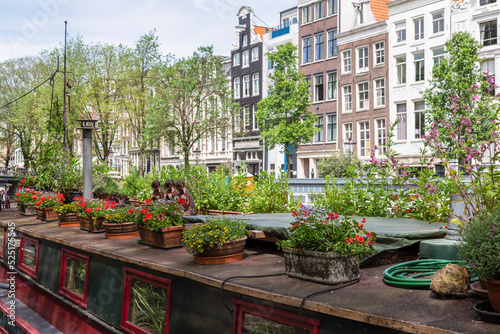 Flower boxes with colorful blooming plants on the roof of a houseboat on the Prinsengracht in Amsterdam.