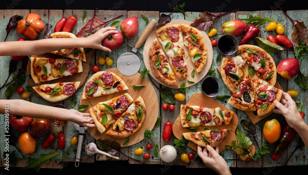 Tomatoes pizza flat lay on shabby old painted wood, woman and kid hands hold the pizza pieces overhead view