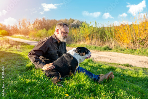Man and Black tri-color English british bulldogs hugging in the park in sunny day. strong friendship and love between humans and dog