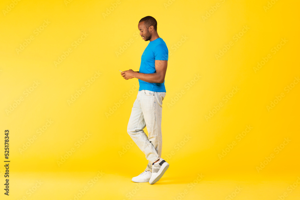 Black Male Using Cellphone Texting Standing Over Yellow Studio Background Black Male Using Cellphone Texting Standing Over Yellow Studio Background