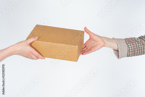Cardboard box in hand. Transferring package from one person to another. Box without inscriptions on white. Concept of targeted delivery. Courier delivery in person. Place to write on box © Grispb