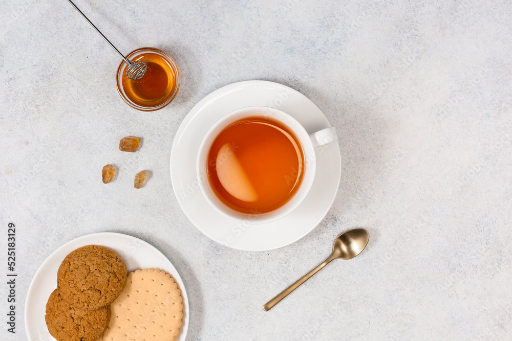 A cup of tea and coockies and honey on a wooden tray. View from above.