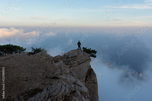 Traveler. A man in the mountains. A young tourist with a backpack is standing on the mountainside. The concept of an active lifestyle, hiking, tourist tours, exploring new places. Beautiful landscape