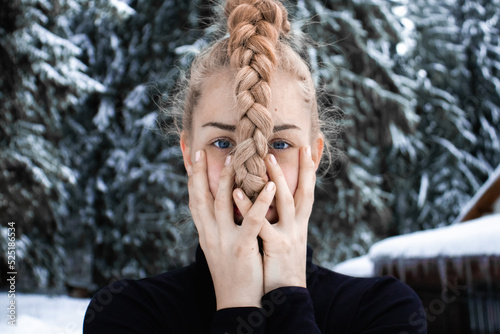 Blonde blue eyed girl, covering the mouth, braided hair, winter