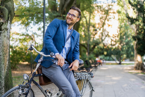 A young smiling, stylish men posing leaned on his bicycle.