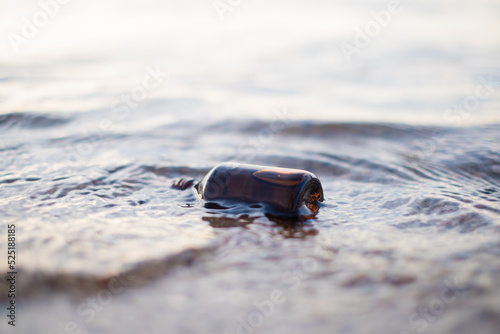 Essential oil bottle on a beach in waves. Little brown medicine bottle in nature background. Organic CBD hemp oil.