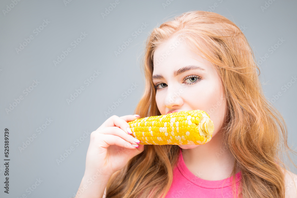 Young beautiful woman eating corn isolated on gray background. Healthy eating concept. Diet. Young beautiful woman eating corn isolated on gray background. Healthy eating concept. Diet.