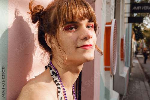 portrait of a smiling young transgender woman leaning against a wall in the street photo