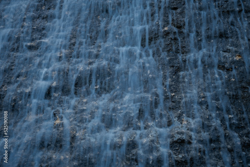 Waterfall texture. Background of the falling purest mountain water. A cascade of blurred motion. Natural abstract background for design. The concept of life, ecology, environmental protection.