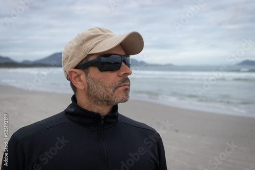 man with sunglasses on the beach looks to the horizon