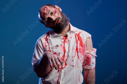 Scary undead zombie looking crazy evil, having blood on shirt and dangerous aggressive bloody look. Eerie apocalyptic corpse with ugly dirty scars and wounds, brain eating demon.