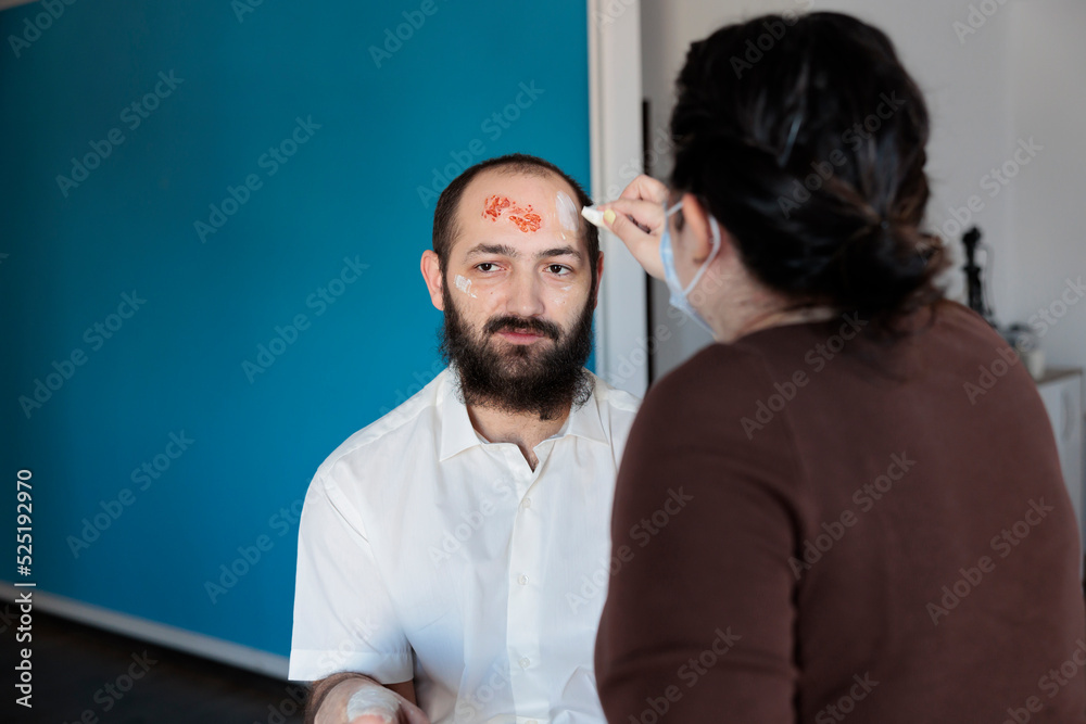 Makeup artist transforming man into zombie with special effects, blood