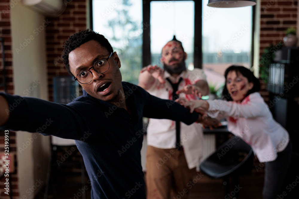 Afraid man running from scary zombies, trying to eat human brain in