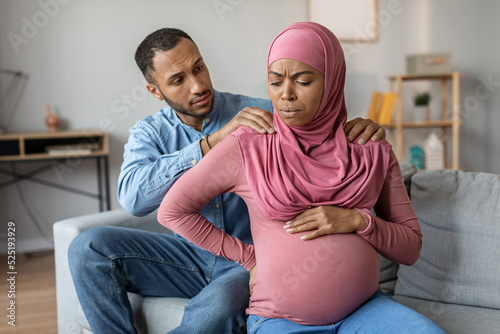 Childbirth Concept. Pregnant Black Muslim Woman Feeling Abdomenal Pain At Home photo