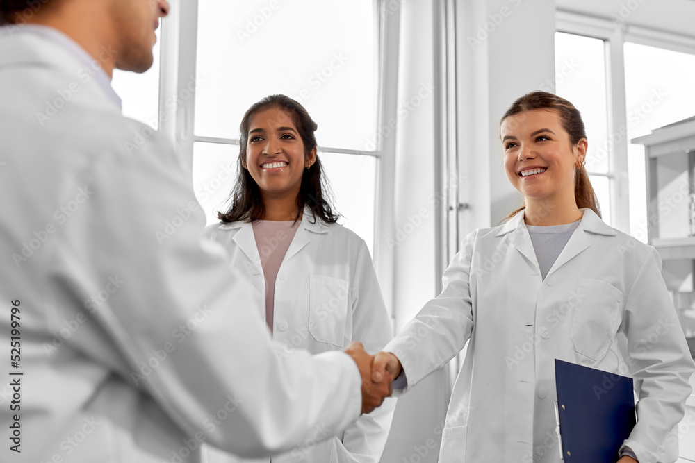 science, work and people concept - international group of happy scientists shaking hands in laboratory science, work and people concept - international group of happy scientists shaking hands in laboratory