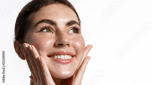 Beauty and skin care. Smiling girl cleansing her skin, rubbing in facial cream, moisturizer gel from blemishes, standing over white background